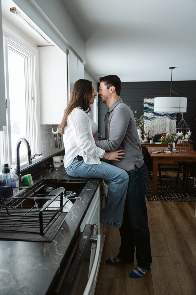 husband and wife standing in kitchen durning home maternity photos in traverse city michigan
