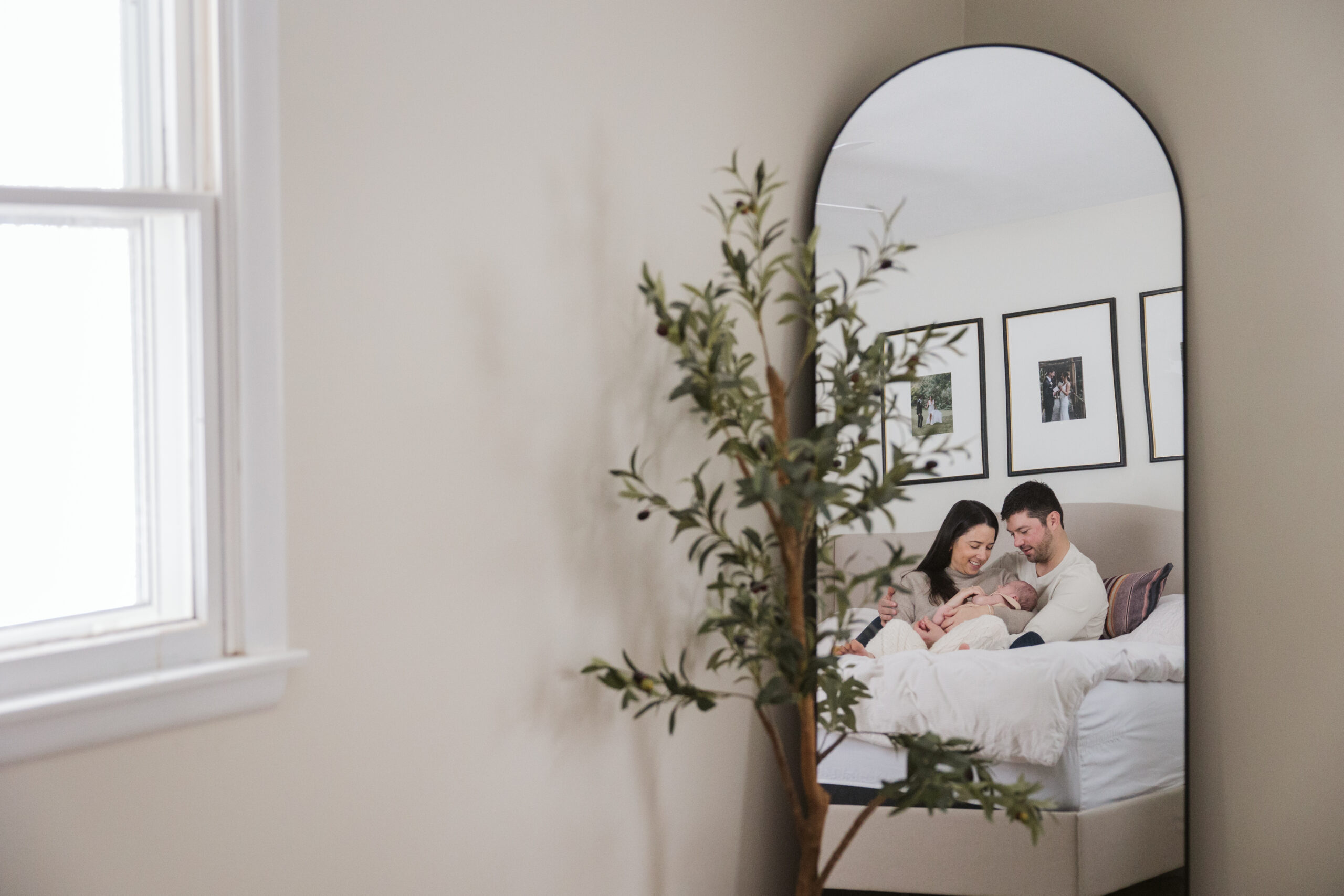 Traverse-city-michigan-newborn-photographer husband and wife holding baby on bed during newborn family photos in traverse city