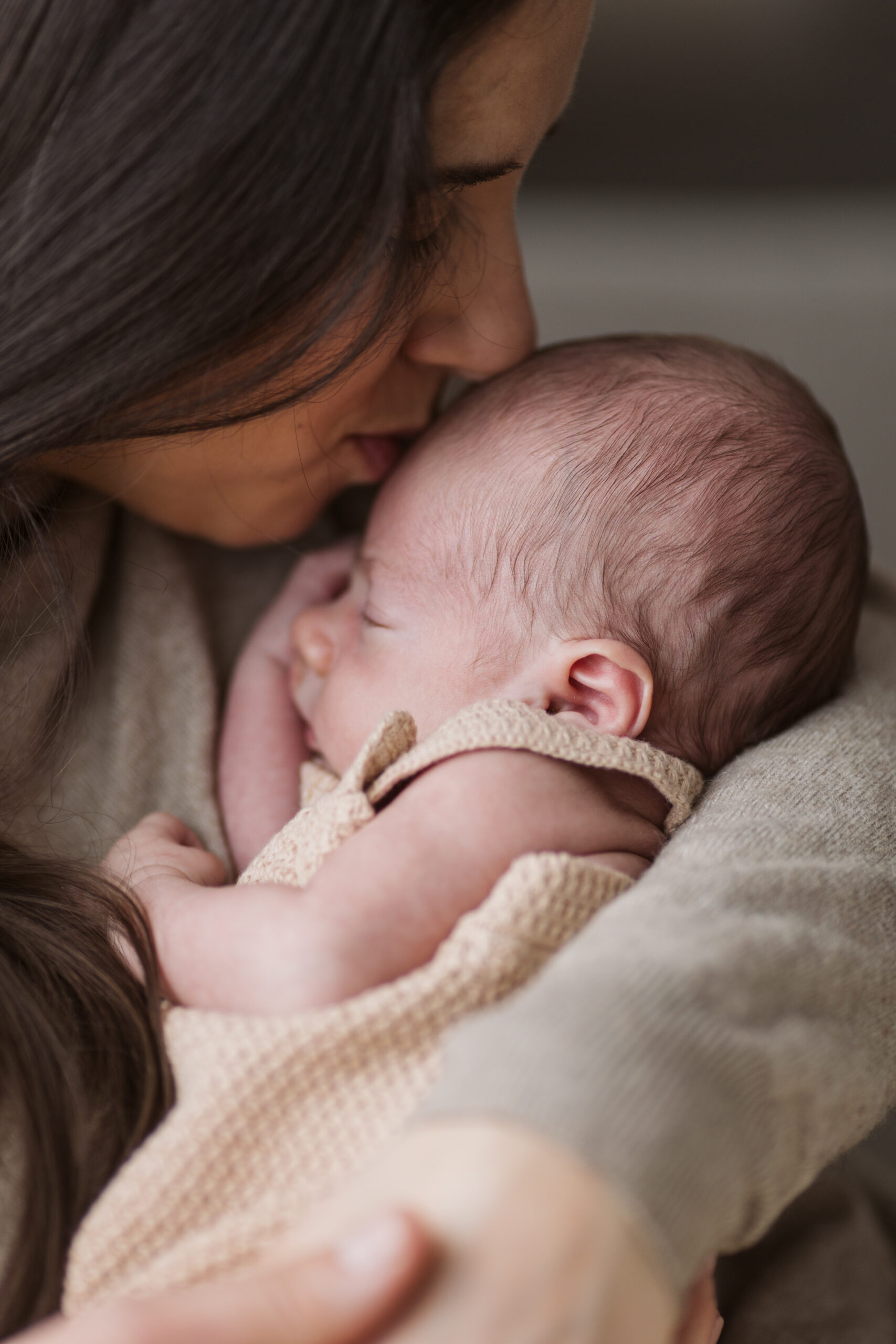 Traverse-city-michigan-newborn-photographer mom kissing newborn son during newborn family photos in traverse city