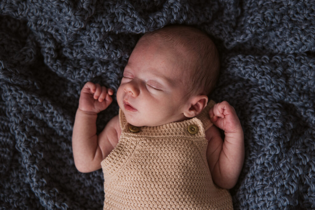baby lying on blanket during newborn family photos in traverse city
