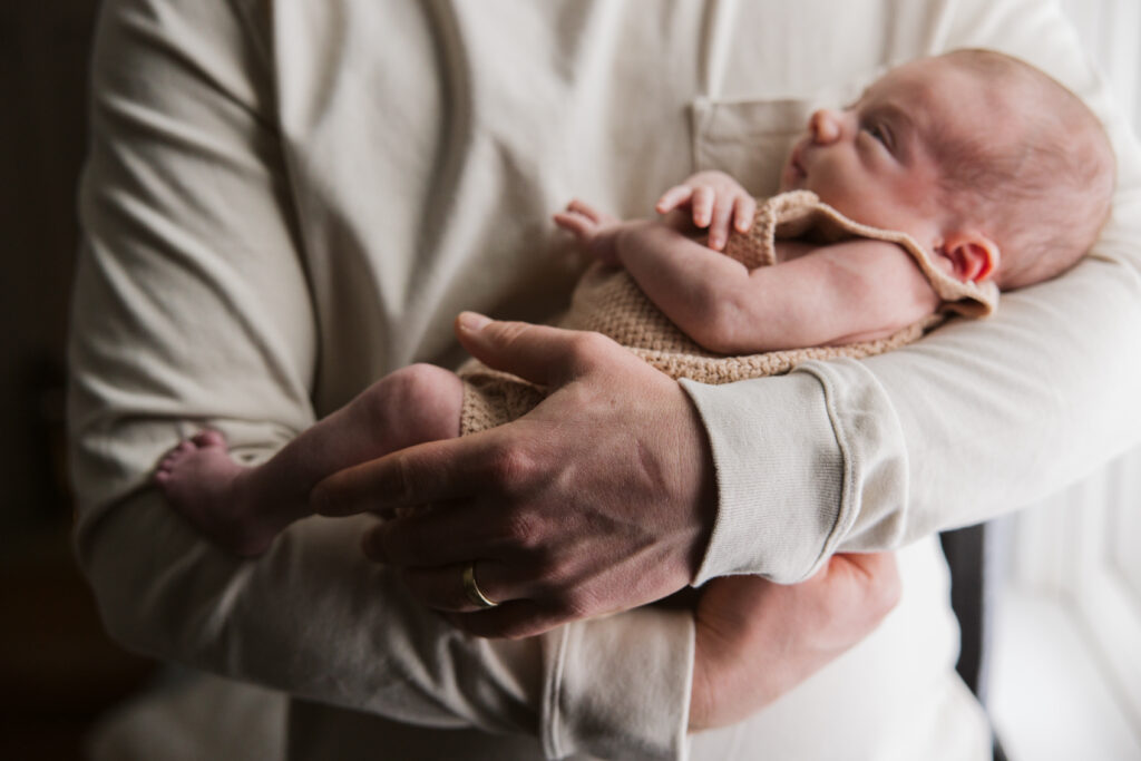 Traverse-city-michigan-newborn-photographer dad holding baby during newborn family photos in traverse city