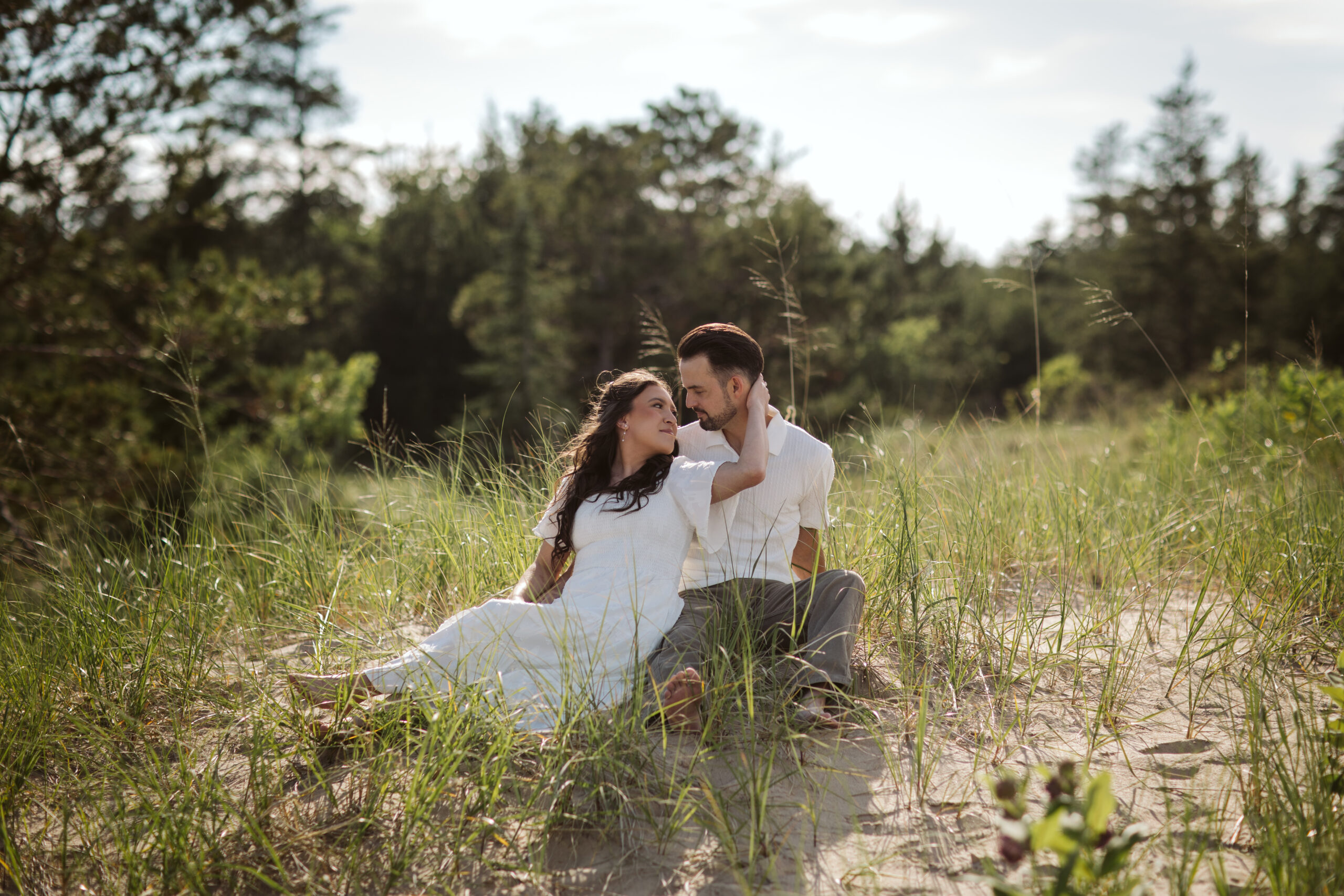 man and woman sitting on glen haven beach in glen arbor michigan during engagement photos