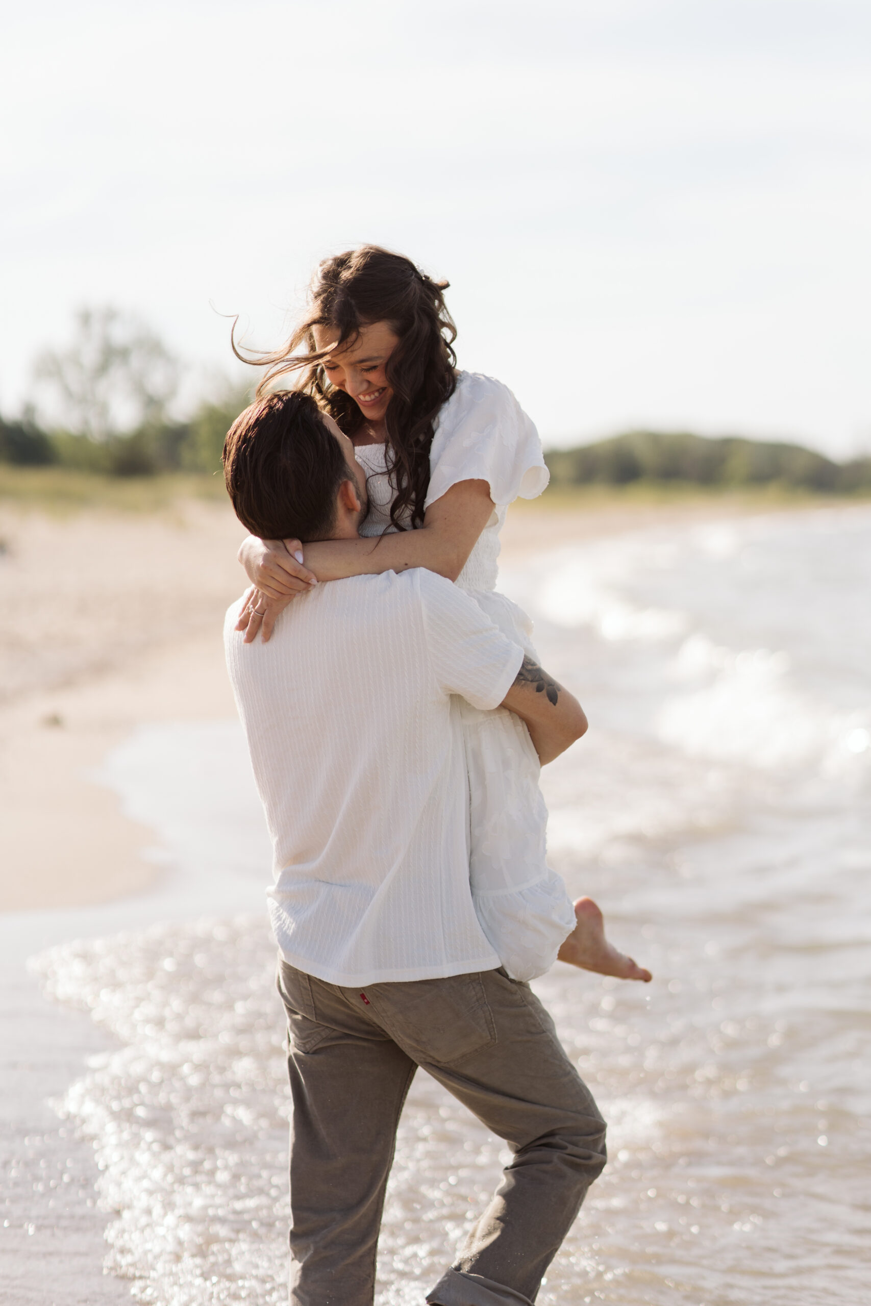man and woman on glen haven beach in glen arbor michigan during engagement photos