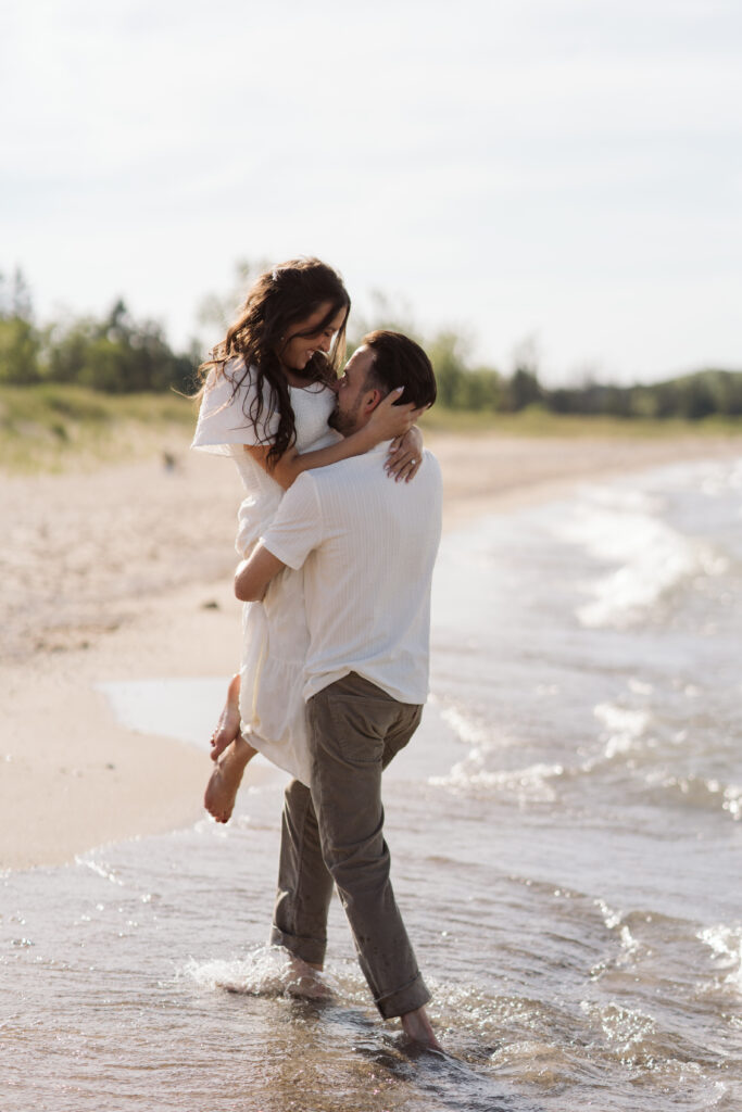 man and woman on glen haven beach in glen arbor michigan during engagement photos